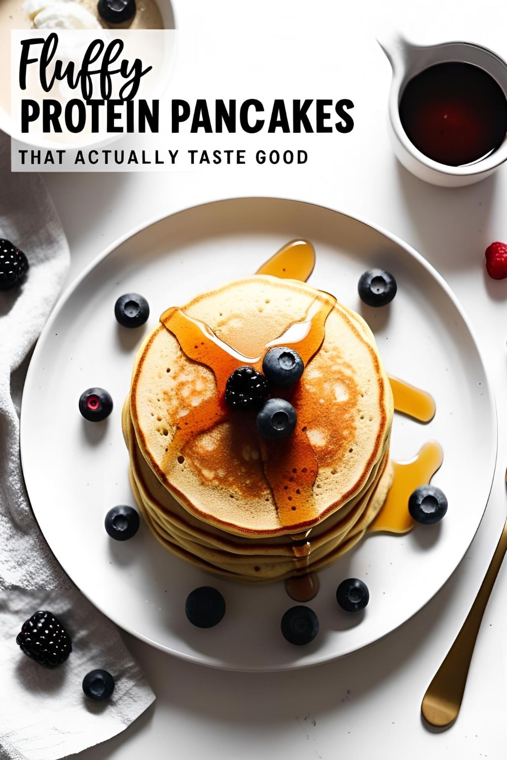 Stack of fluffy protein pancakes topped with berries and drizzled with maple syrup on white plate