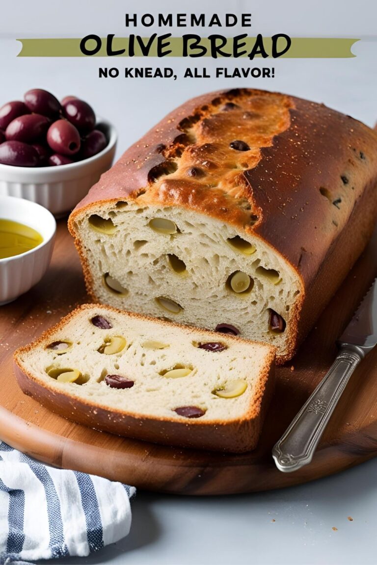 A freshly baked loaf of olive bread with a golden crust and visible olive pieces.