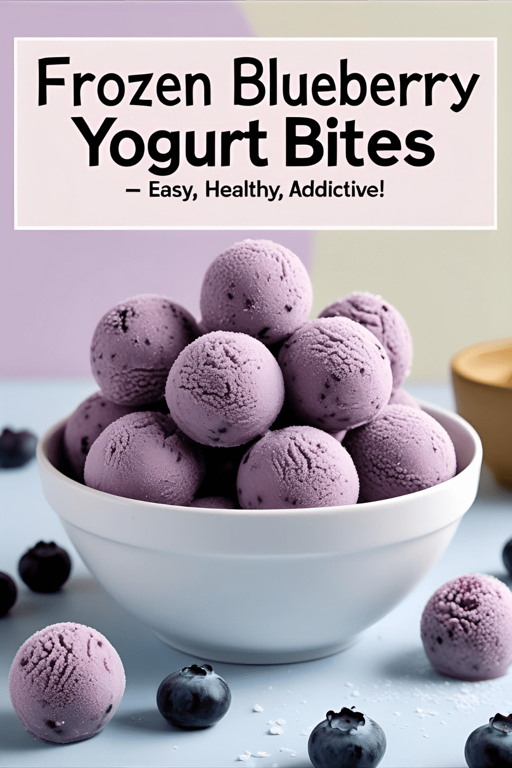 Frozen blueberry yogurt bites stacked in a bowl with frosty details and soft pastel background