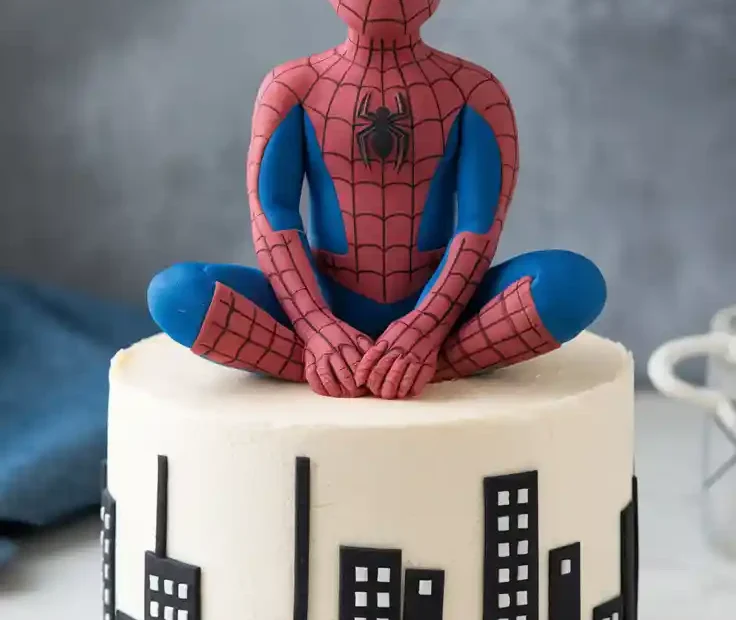A finished DIY fondant Spiderman cake topper sitting on a birthday cake, with a text overlay that reads, "You Can Make This!"