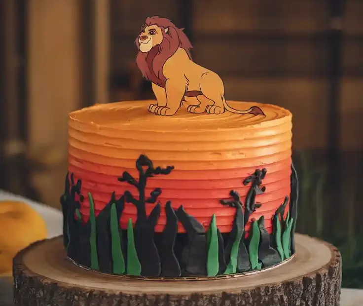 The finished Lion King cake with a sunset buttercream design and text overlay that says "The Easiest Lion King Cake You'll Ever Make."