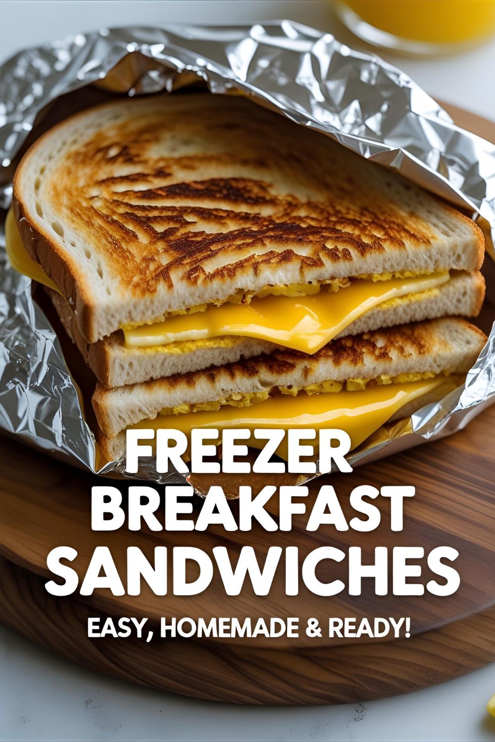 Sliced breakfast sandwich with egg, cheese & bacon on wooden board ready to go