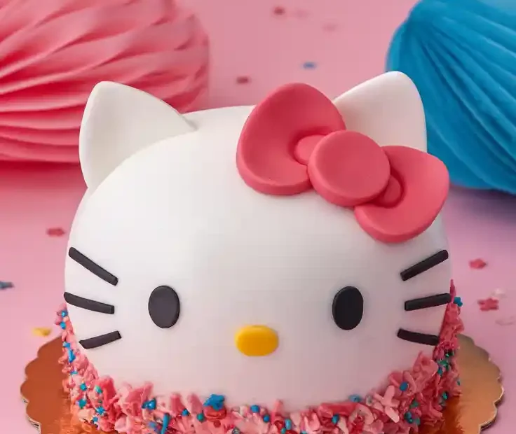 A bright, perfect Hello Kitty face cake on a cheerful pink background. Playful, cute text overlay says: "Hello, Cuteness!"