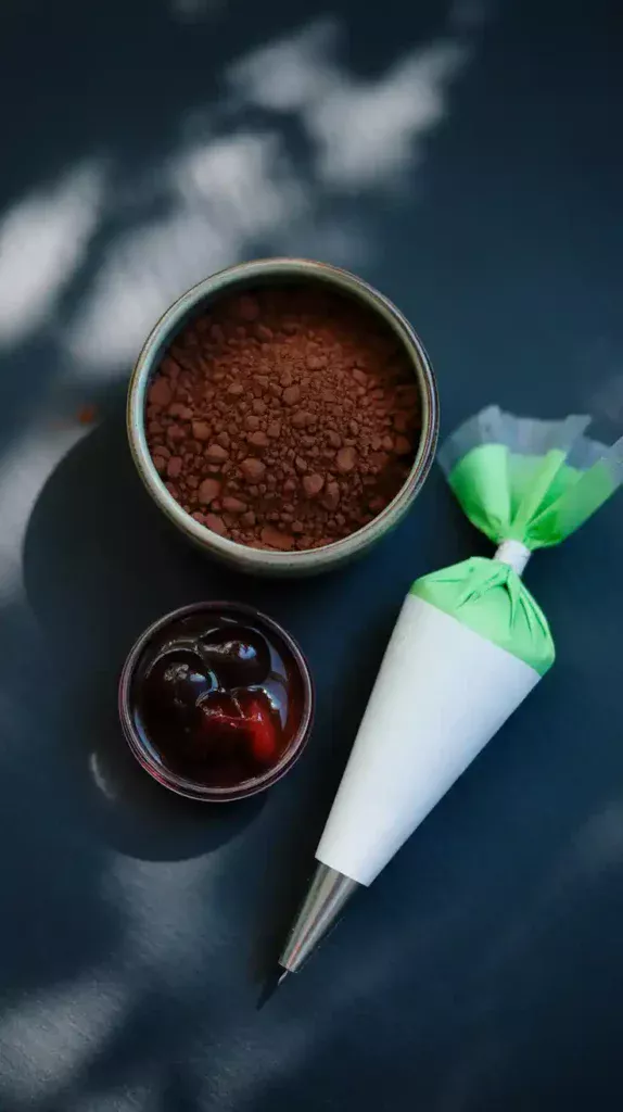 A flat lay collage showing the key elements for a Billie Eilish cake: black cocoa powder, red cherry filling, and neon green frosting.