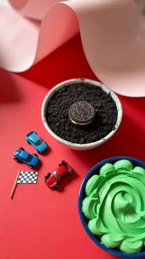 A flat lay collage showing the elements for a race car cake: crushed Oreos, green frosting, toy cars, and a checkered flag.