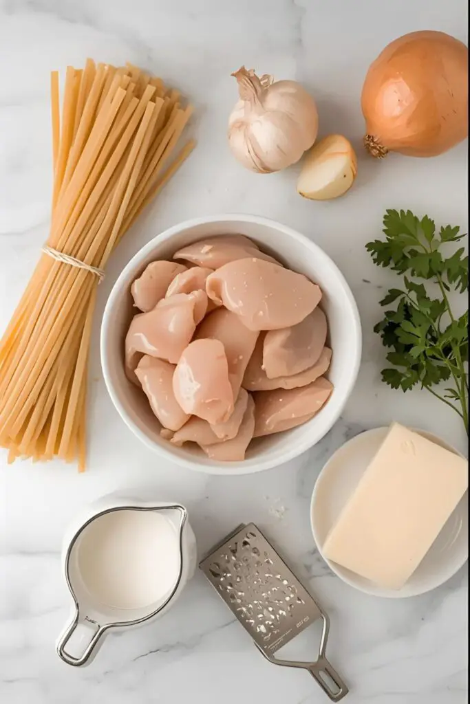 A flat lay of ingredients for creamy chicken pasta, including pasta, chicken, cream, and Parmesan cheese.