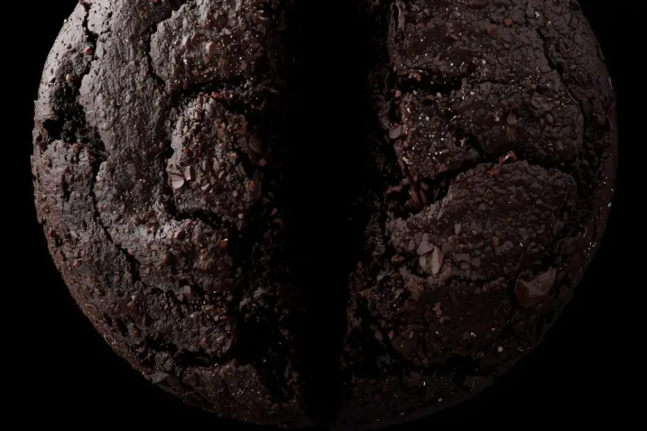 Text overlay "Dark Cacao Cookies" on a background image of nearly-black, glossy cookies with crackled tops, sprinkled with white flaky sea salt.