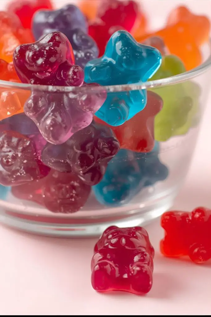 A close-up of colorful homemade Kool-Aid gummy bears in a clear bowl, showcasing their texture and vibrant colors.