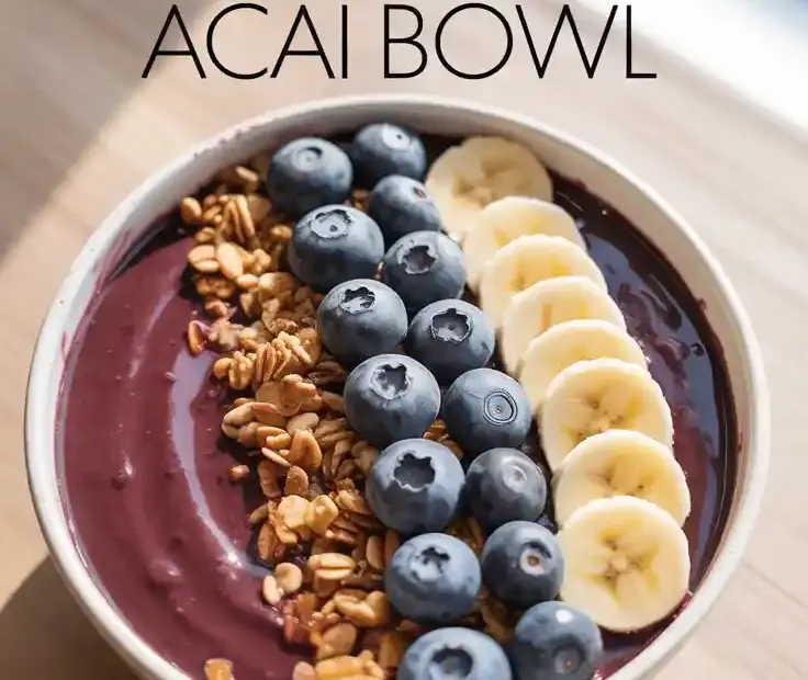 A beautiful, thick, homemade acai bowl in a coconut shell, artfully decorated with rows of fresh fruit, granola, and coconut flakes.