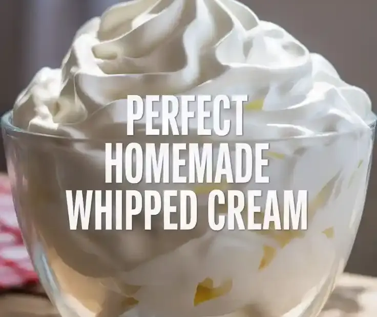 A glass bowl filled with thick and fluffy homemade whipped cream, showing perfect, stiff peaks.