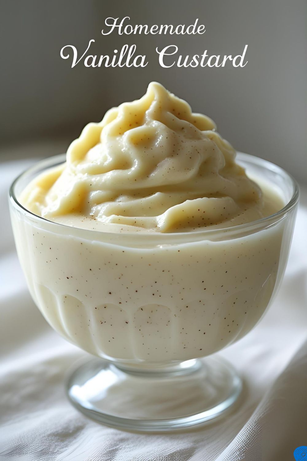 A glass bowl of creamy homemade vanilla custard, showing off the rich texture and specks of real vanilla bean.