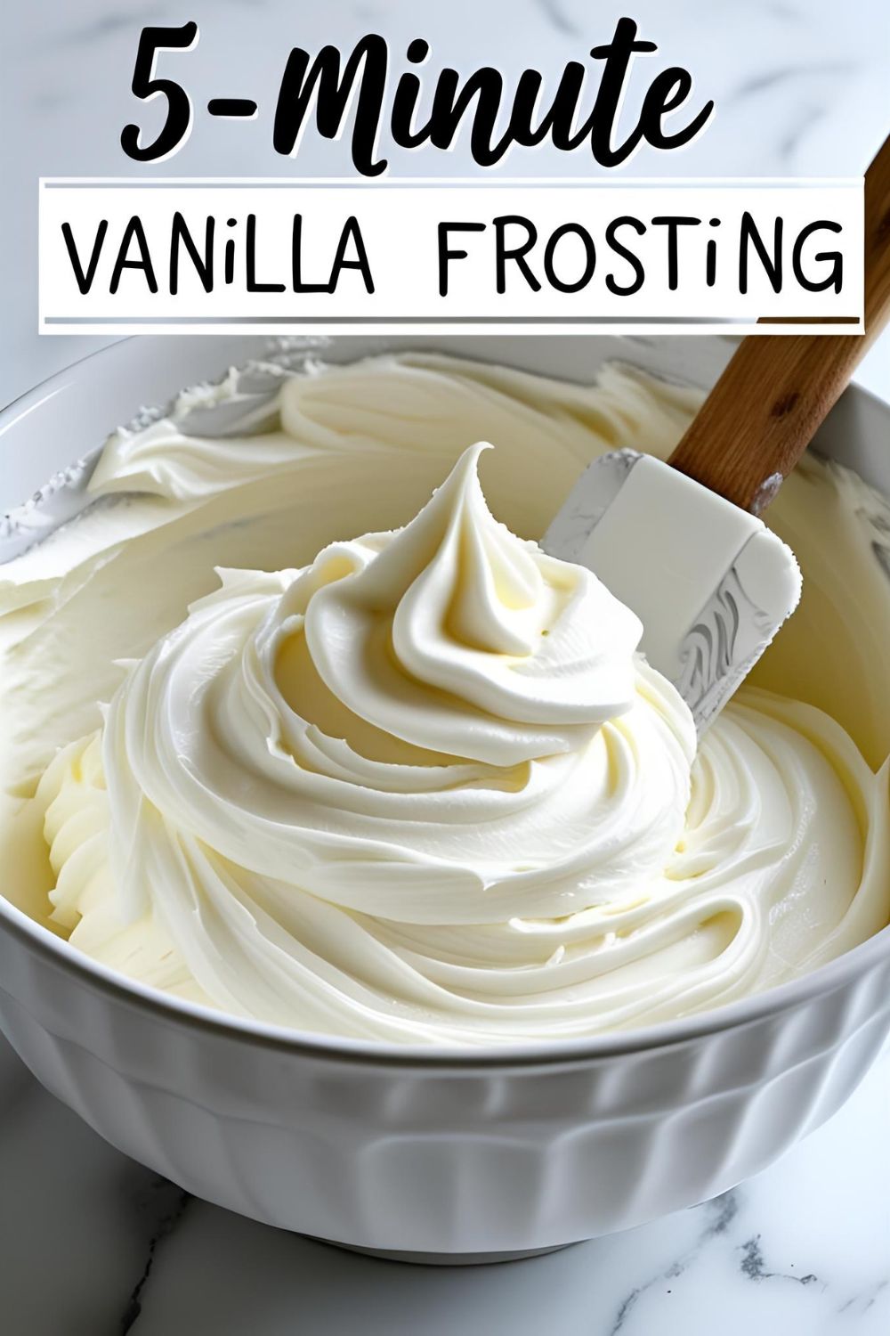 A white bowl filled with fluffy homemade vanilla buttercream frosting, with a spatula ready to spread it.