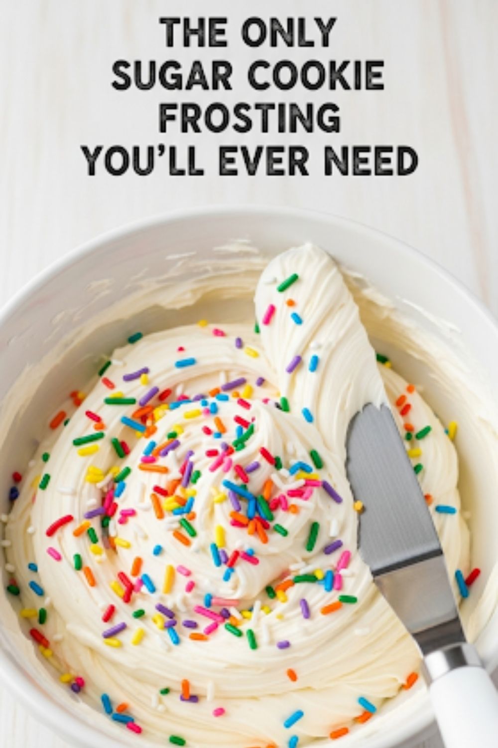 Text overlay "The Best Sugar Cookie Frosting" over a vibrant image of a bowl of fluffy white buttercream frosting with a spatula creating perfect swoops and swirls.